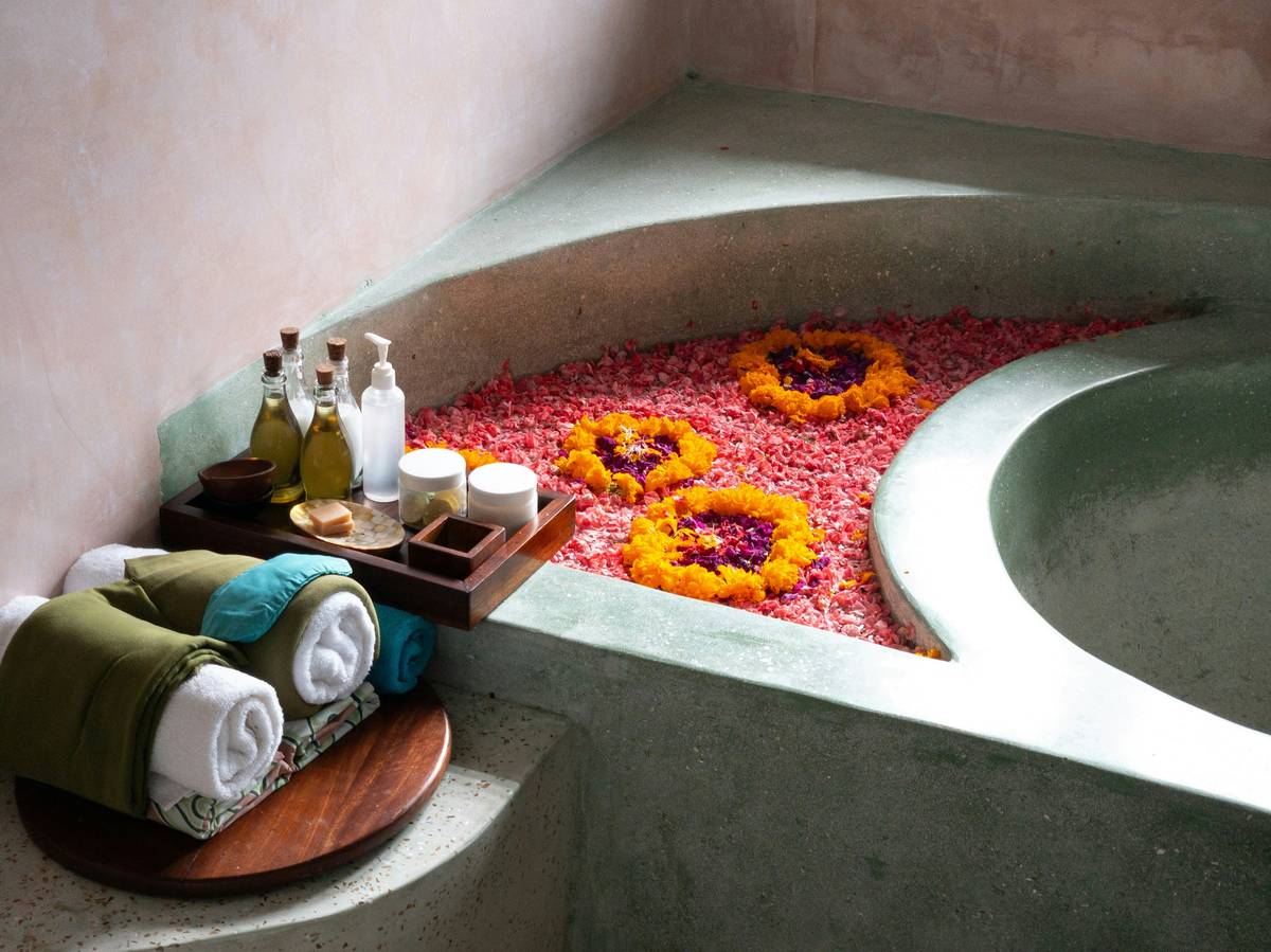 aromatherapy scented flower sukin energise bath in warm morning light with fresh hibiscus petals floating